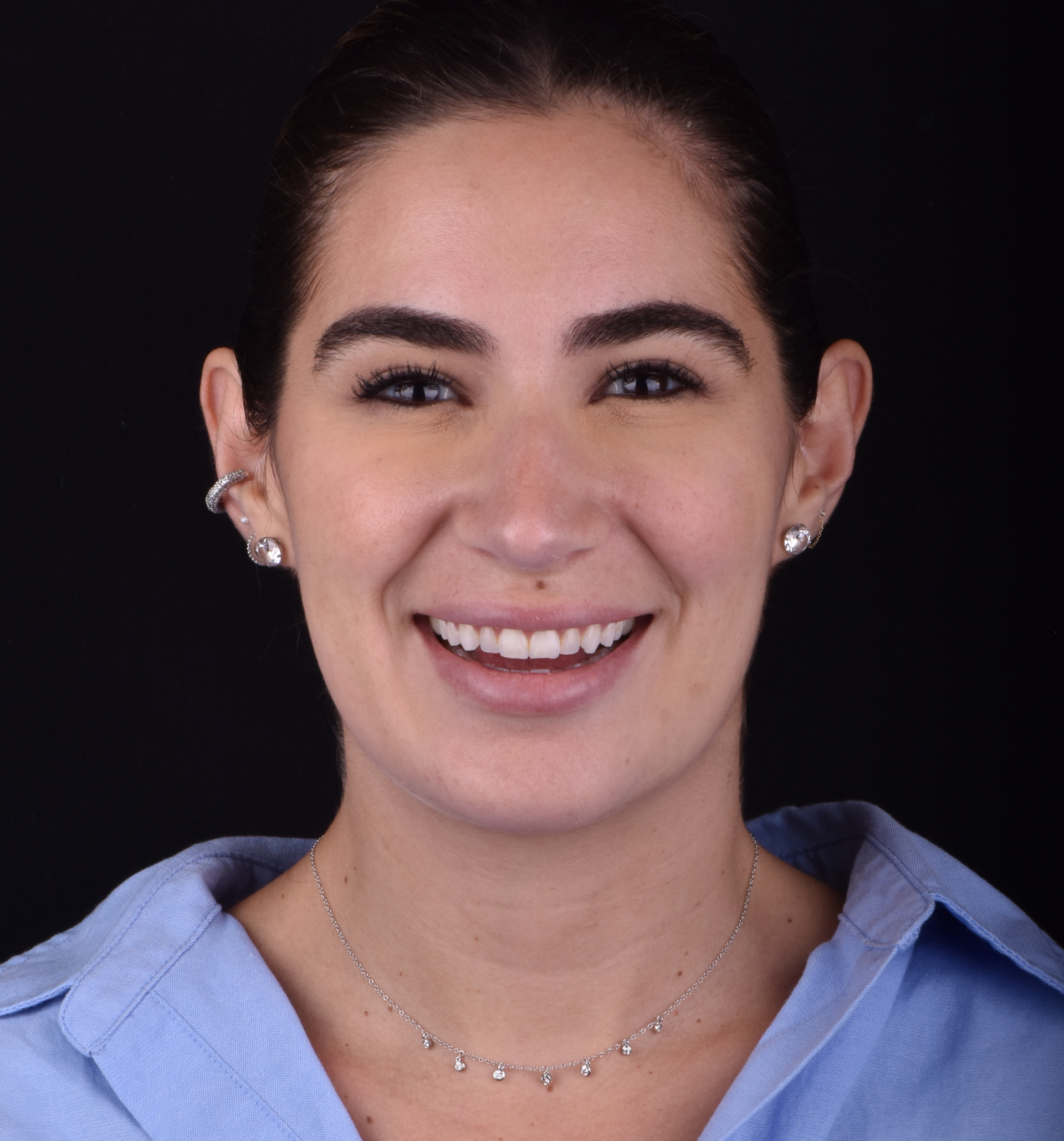 Smiling person in a blue shirt on a dark background