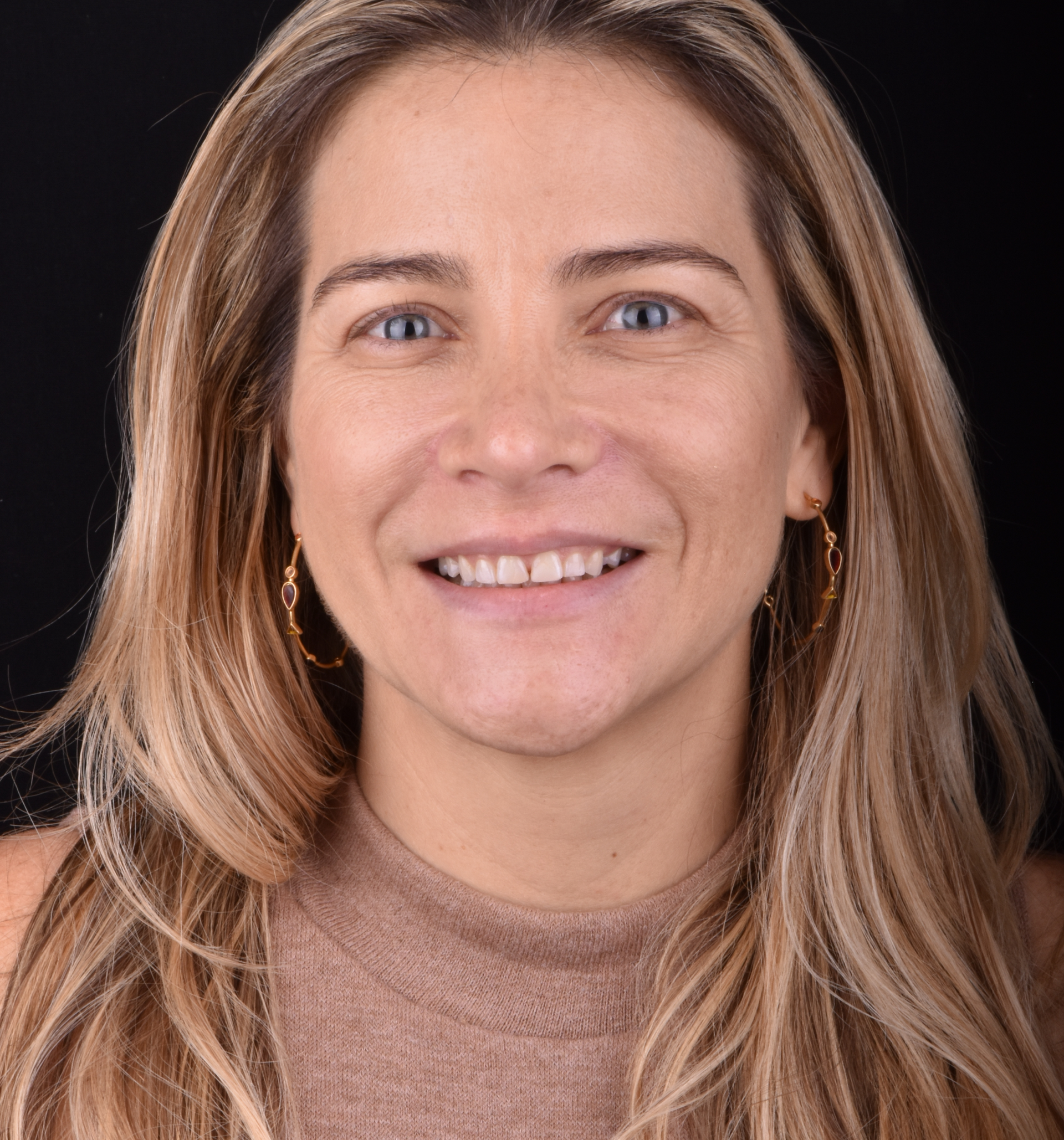 Smiling woman with long highlighted hair against a dark background