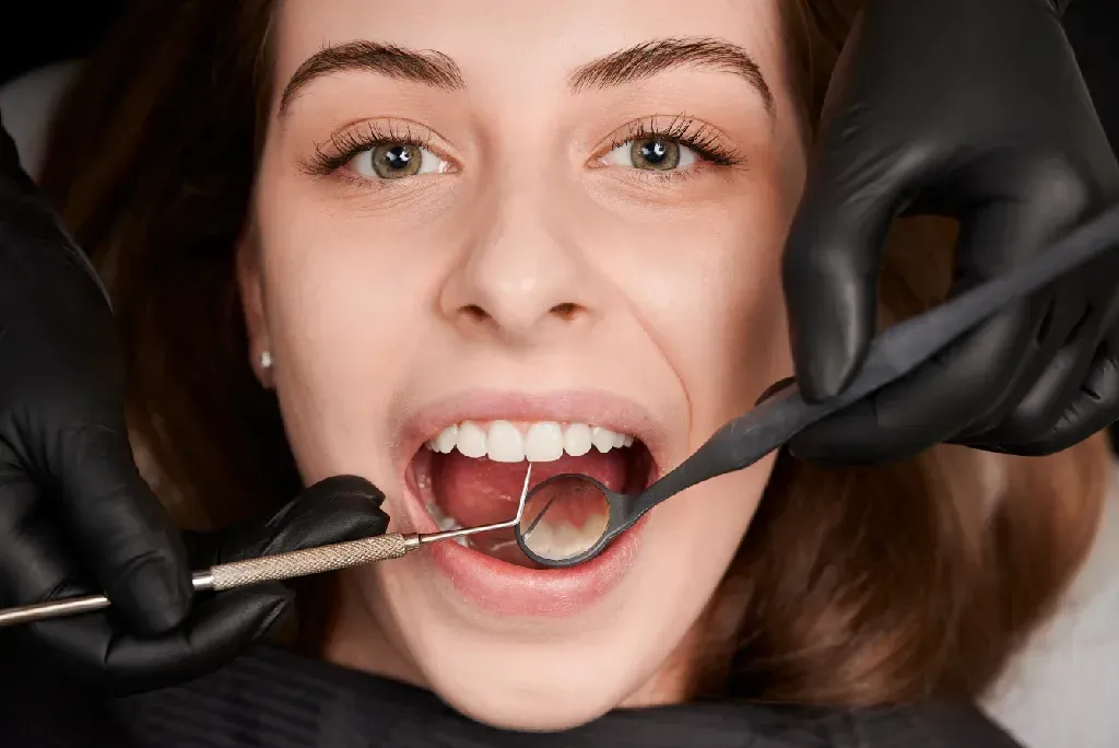 Close-up of a woman getting her teeth examined by a gloved dentist