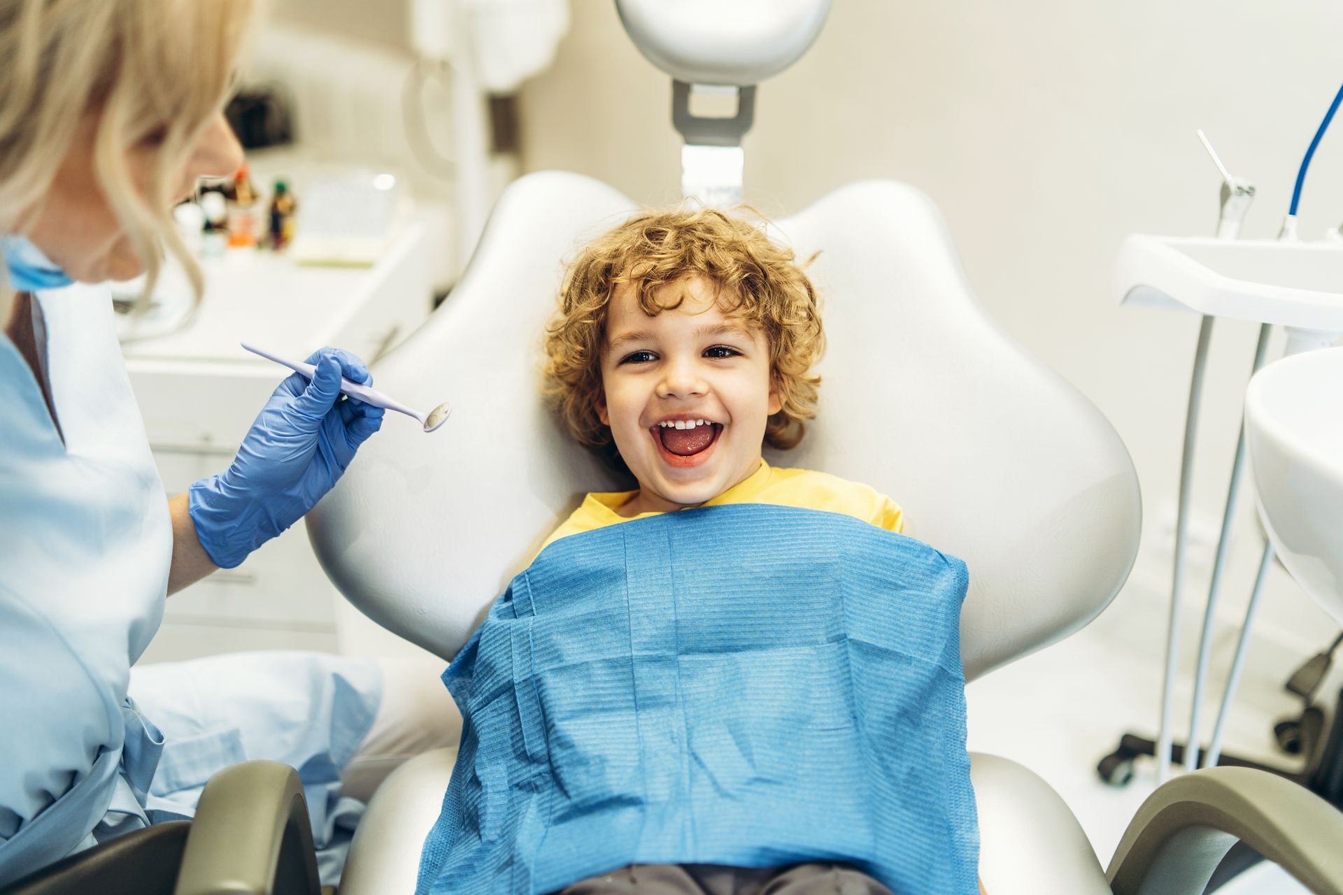 Child smiling in a dental chair while a dentist prepares a checkup