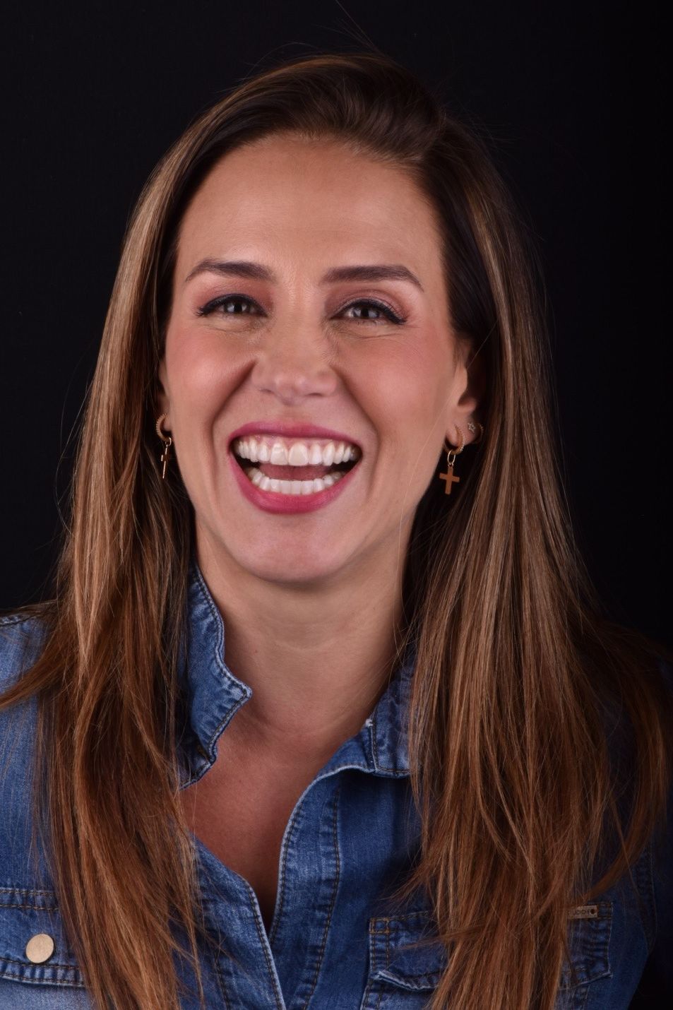Smiling woman in a denim shirt against a black background