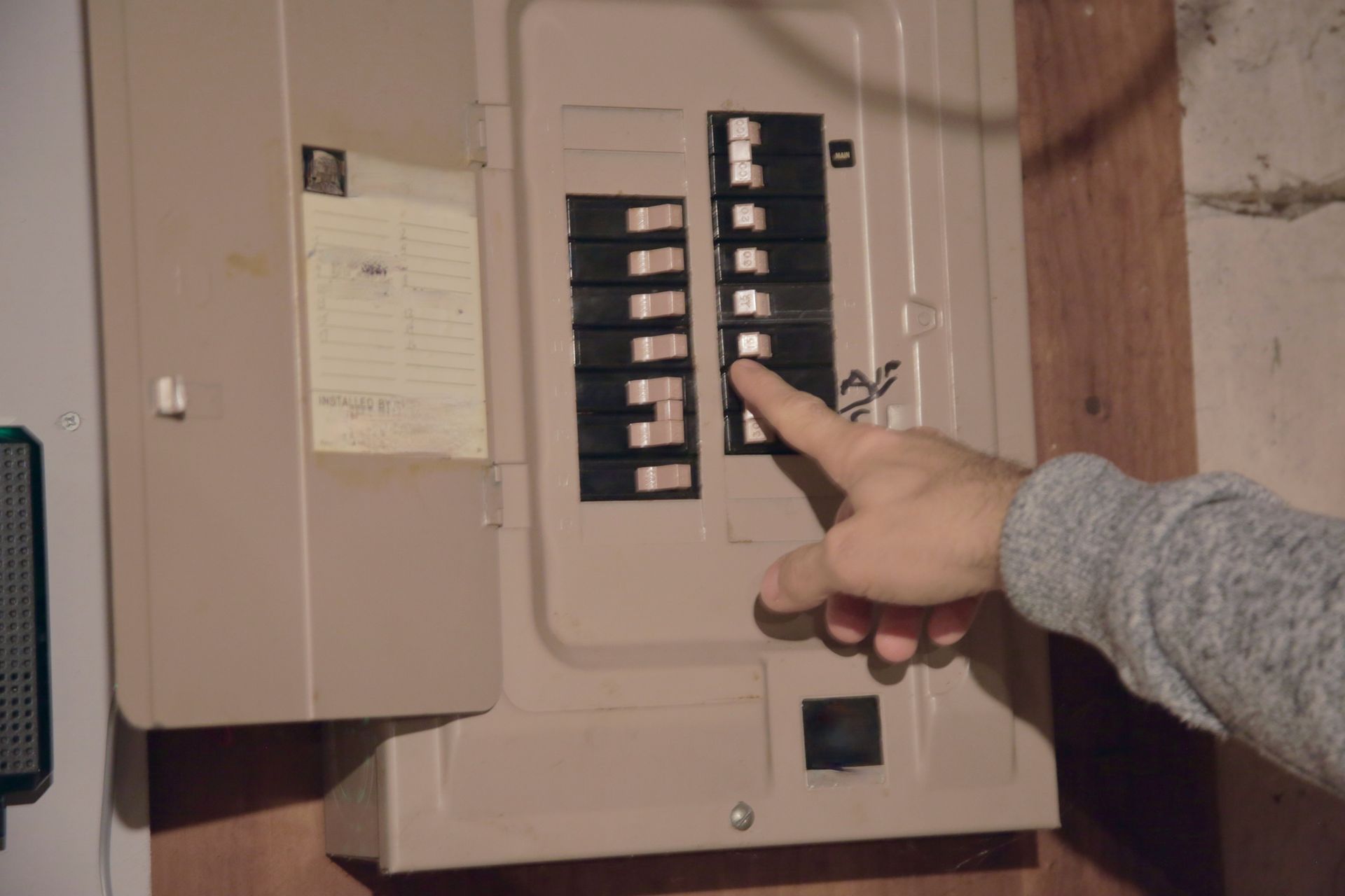 Anderson Electric electrician inspecting an outdated electrical panel showing signs of corrosion.