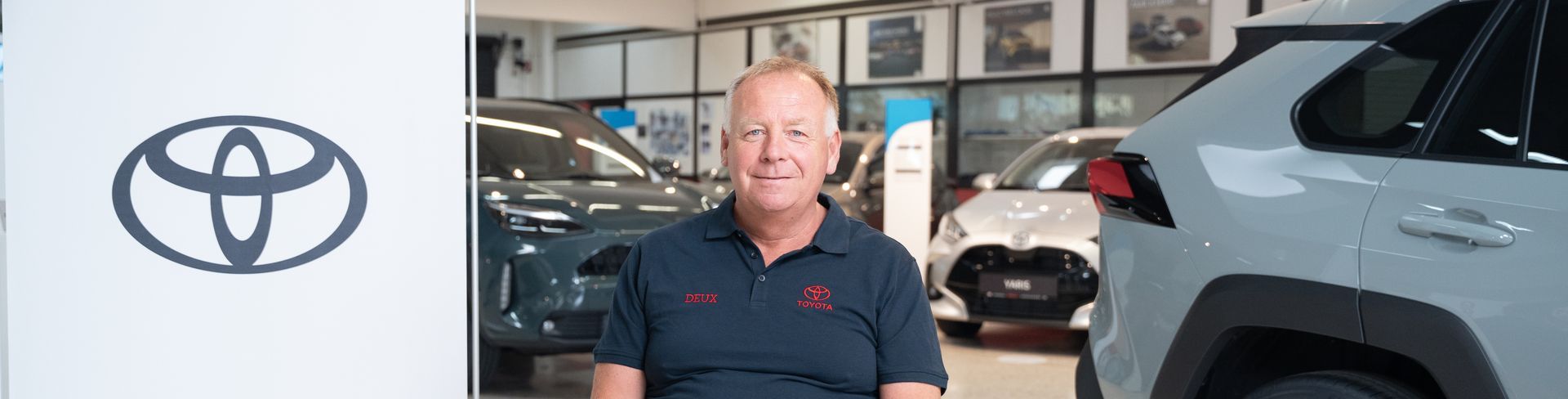 Mitarbeiter sitzend vor Autos des Autohauses Müller in Sarasdorf. Toyota-Logo auf der linken Seite.