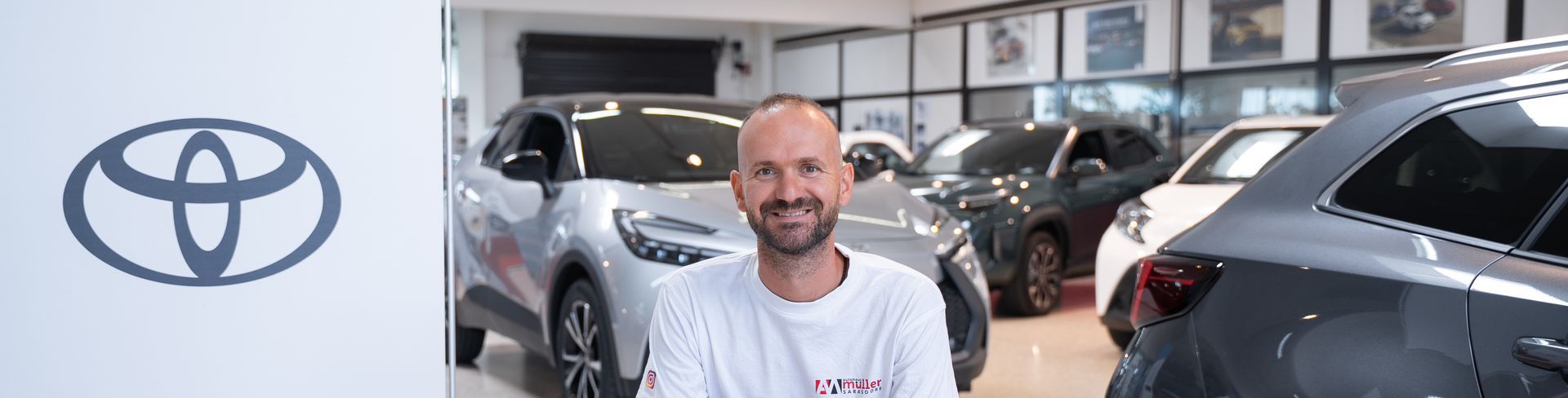 Mitarbeiter sitzend vor Fahrzeugen Autohauses Müller in Sarasdorf. Toyota-Logo auf der linken Seite.