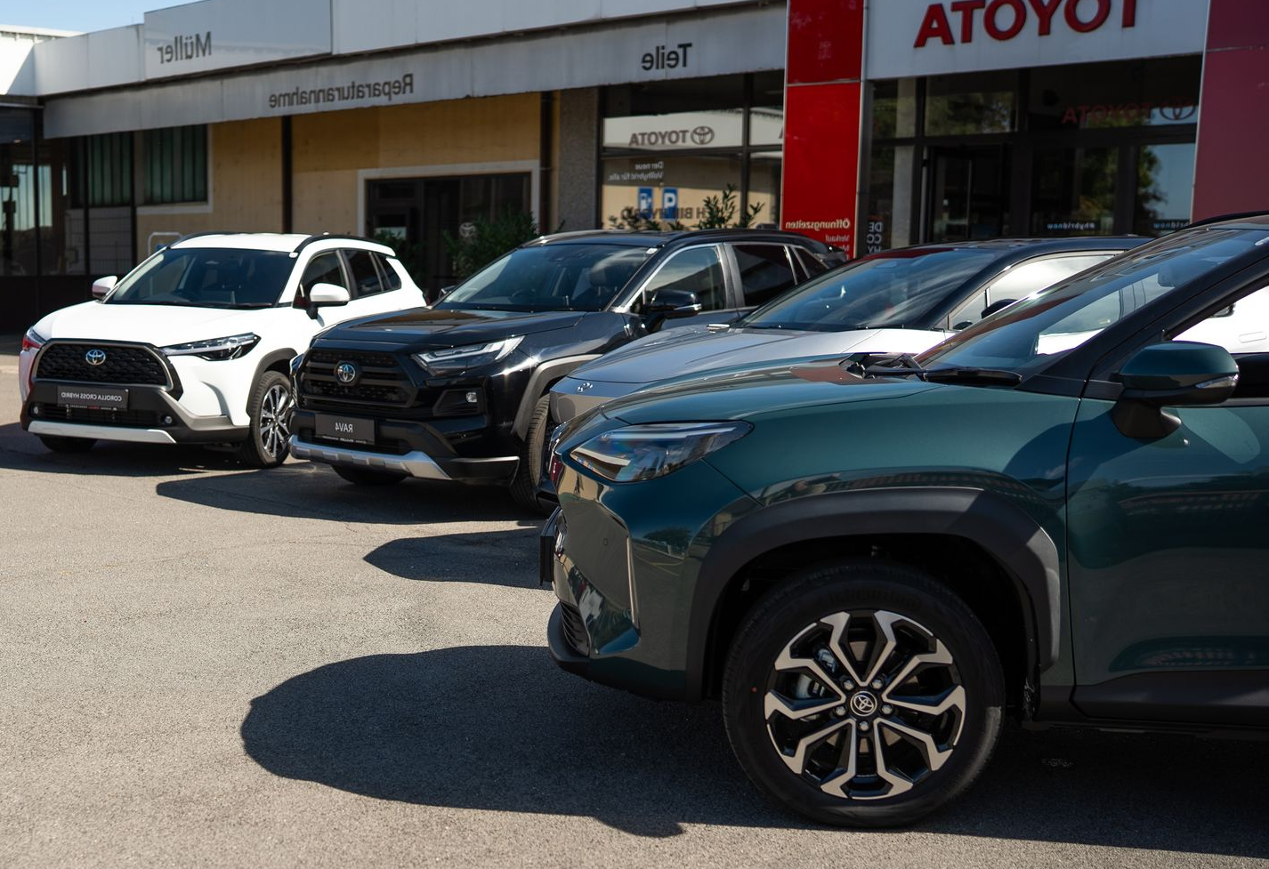 Vor einem Toyota-Händler geparkte Autos: weiße, schwarze, graue und grüne SUVs.