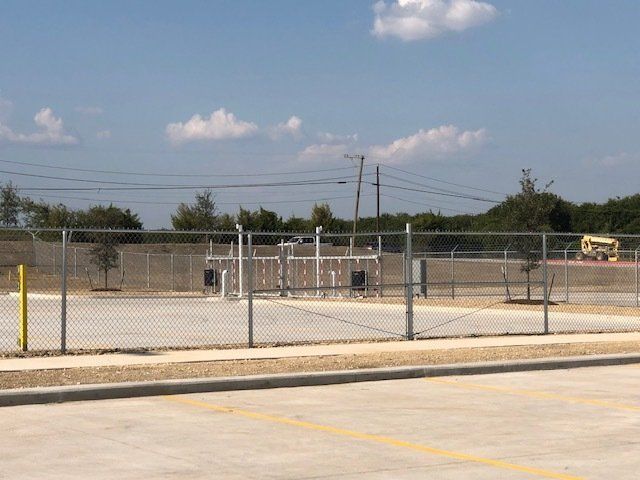 A chain link fence surrounds a parking lot on a sunny day
