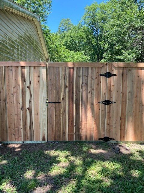 A wooden fence with a gate in the backyard of a house.