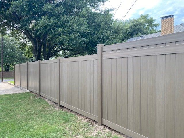 A tan wooden fence surrounds a lush green yard.