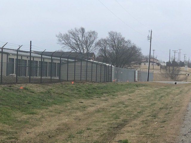 A fenced in area with a building in the background.