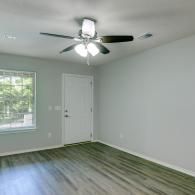 Empty room with gray walls, wood-look floor, window, door, and ceiling fan light