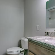 Small bathroom with toilet, granite vanity, and wall mirror.