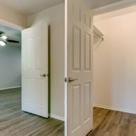 Open white doors in a bright room with wood-look flooring and beige walls