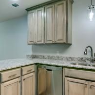 Empty kitchen corner with light wood cabinets, granite countertops, and a stainless sink/faucet.
