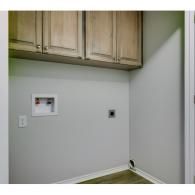 Empty laundry nook with wall cabinets, hookups, and outlets on a light gray wall.