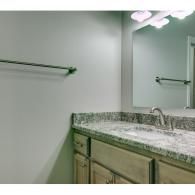Bathroom vanity with granite countertop, sink, mirror, and wall-mounted towel bars