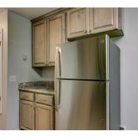 Small kitchen with light wood cabinets, granite countertop, and stainless steel refrigerator.