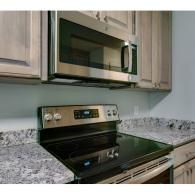 Kitchen with stainless steel microwave above a black stove and granite countertops