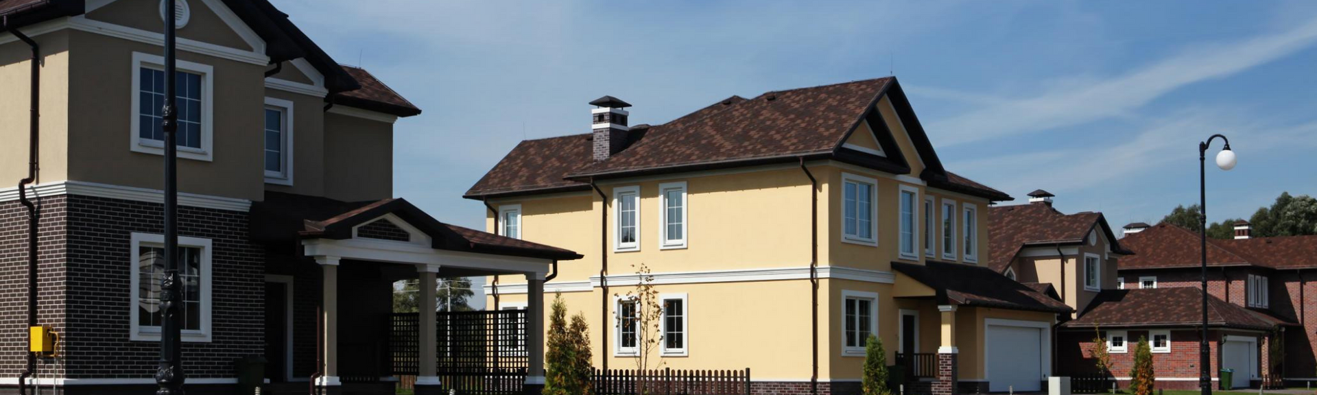 Yellow house with a red roof in a suburban neighborhood under a clear sky