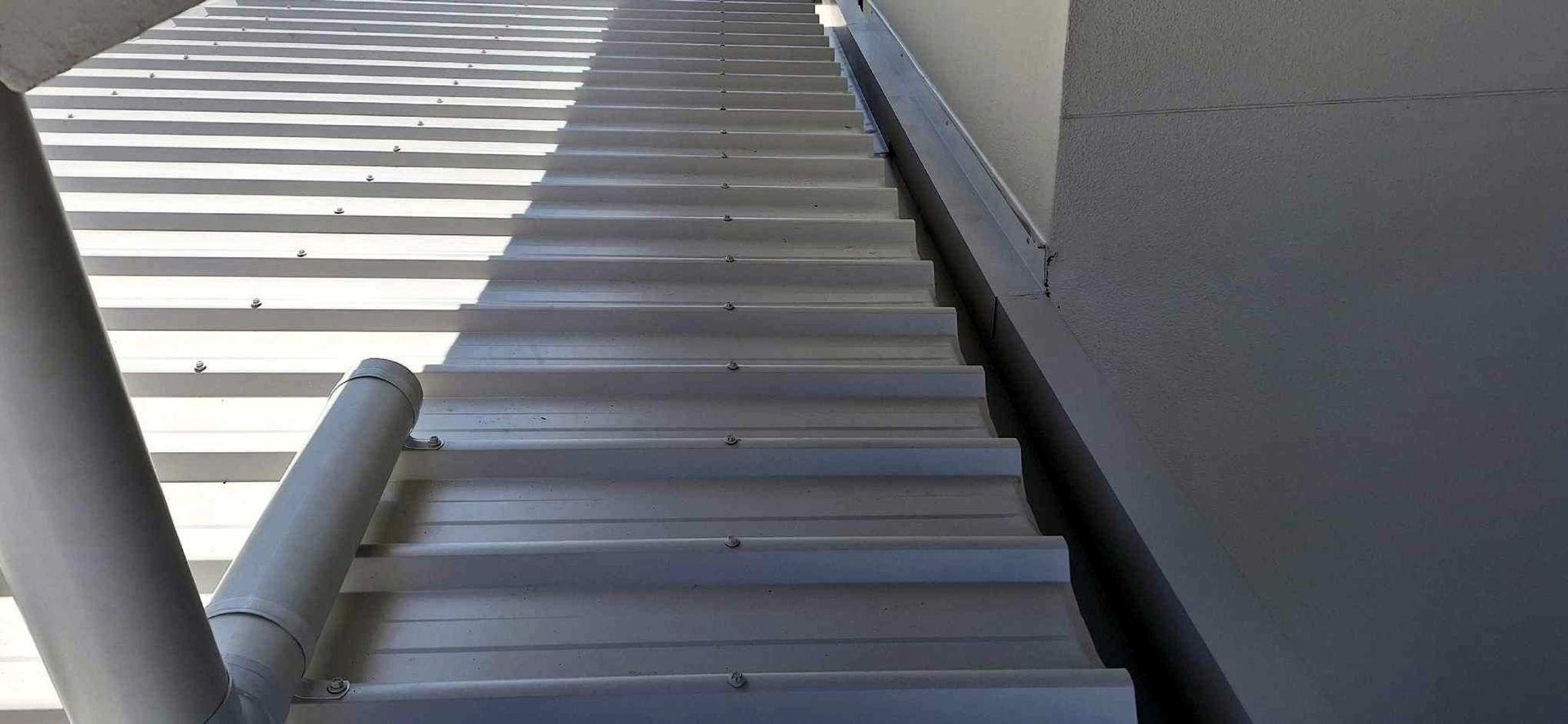 A Man Is On The Roof Of A House — Coastal Roof & Gutter Services In Coolum Beach, QLD
