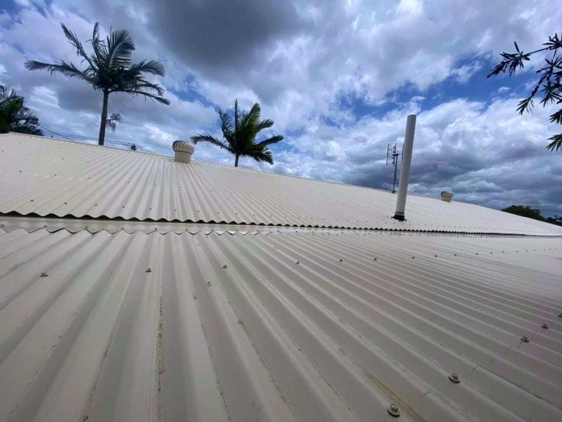 A Man On A Ladder Is Installing A Camera On The Side Of A House — Coastal Roof & Gutter Services In Coolum Beach, QLD