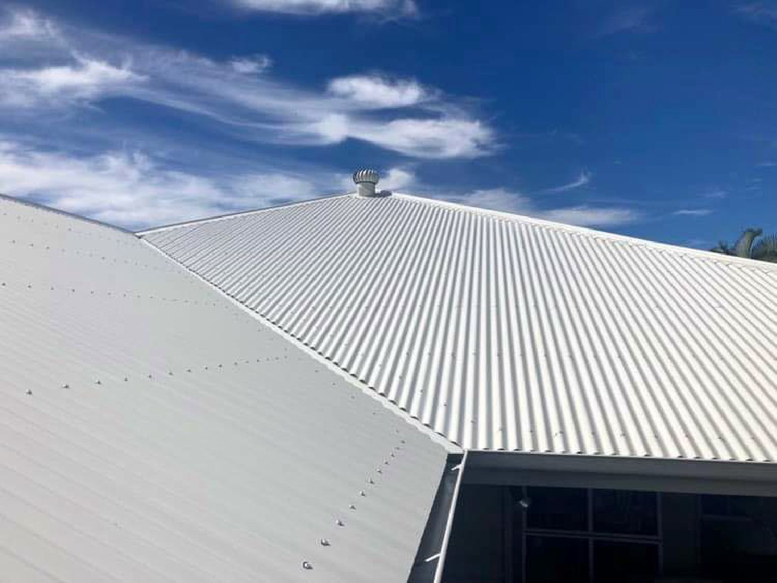 A Man Is Working On The Roof Of A House — Coastal Roof & Gutter Services In Coolum Beach, QLD
