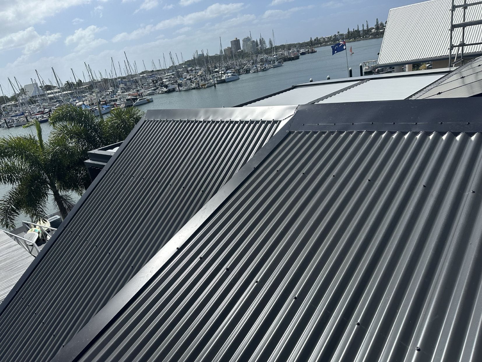 A Man Is Climbing A Roof With A Rope Attached To Him — Coastal Roof & Gutter Services In Coolum Beach, QLD