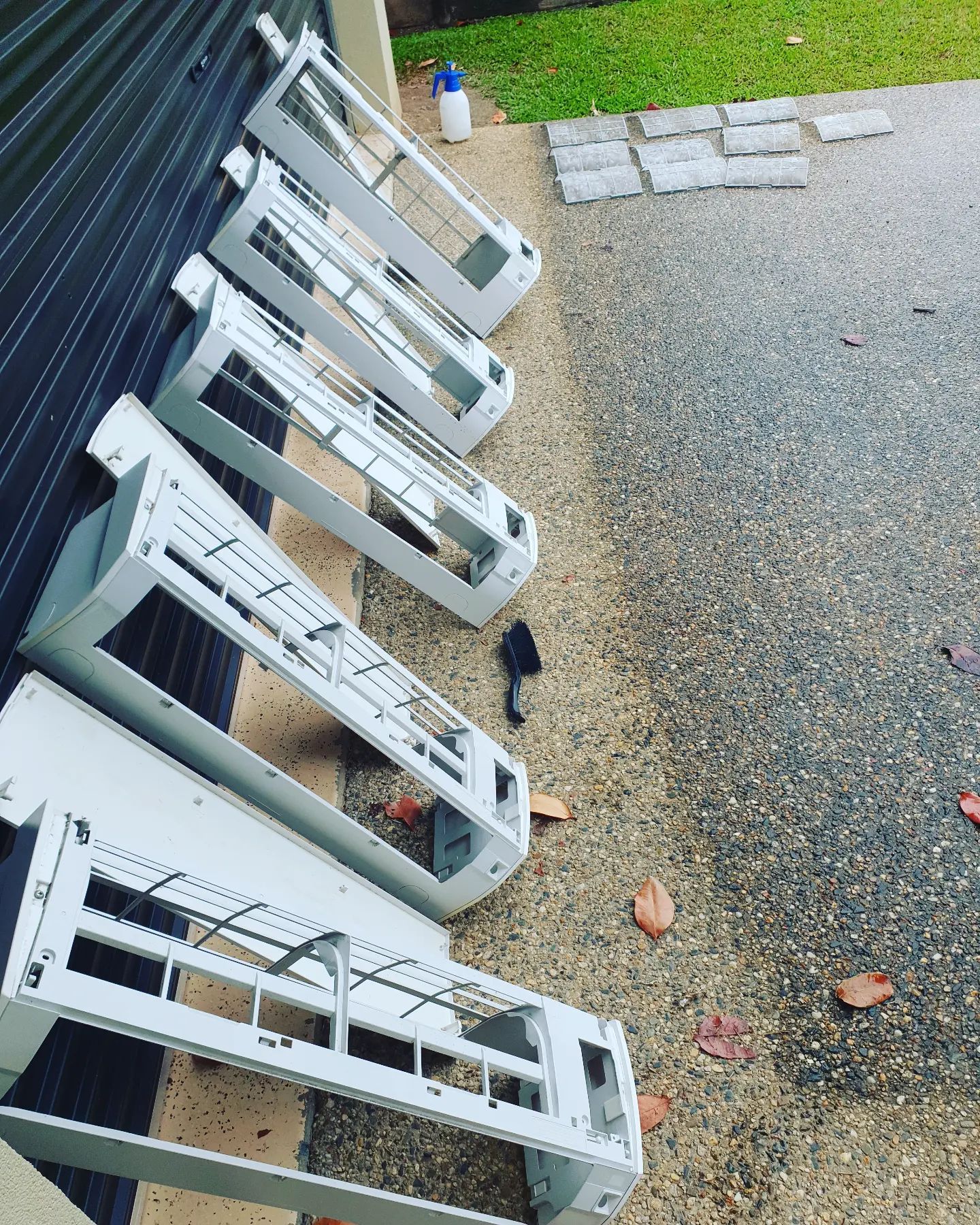 A White Air Conditioner Covers Laid out On a Concrete Driveway — Coach That Cleans in Speewah, QLD