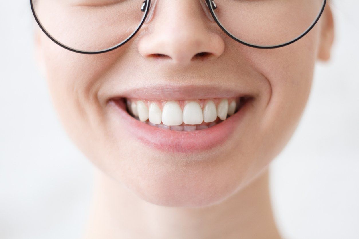 A close up of a woman wearing glasses and smiling.