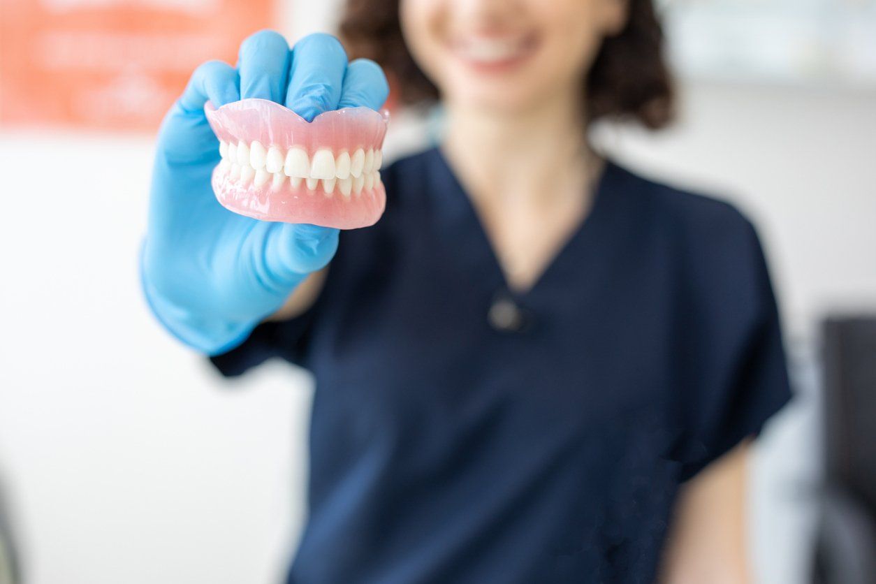 A dentist is holding a denture in her hand.