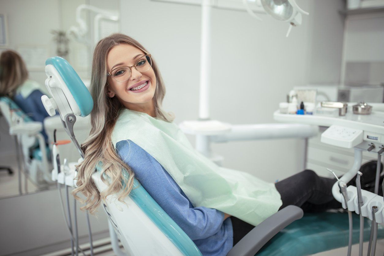 A woman is sitting in a dental chair and smiling.