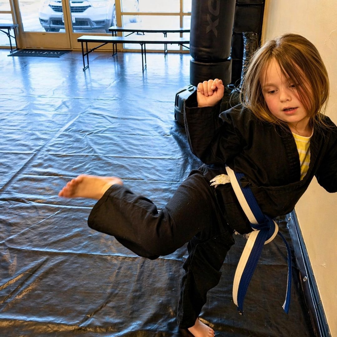 Two boys on a mat practicing Jiu-Jitsu. One boy is on top, giving a thumbs-up.