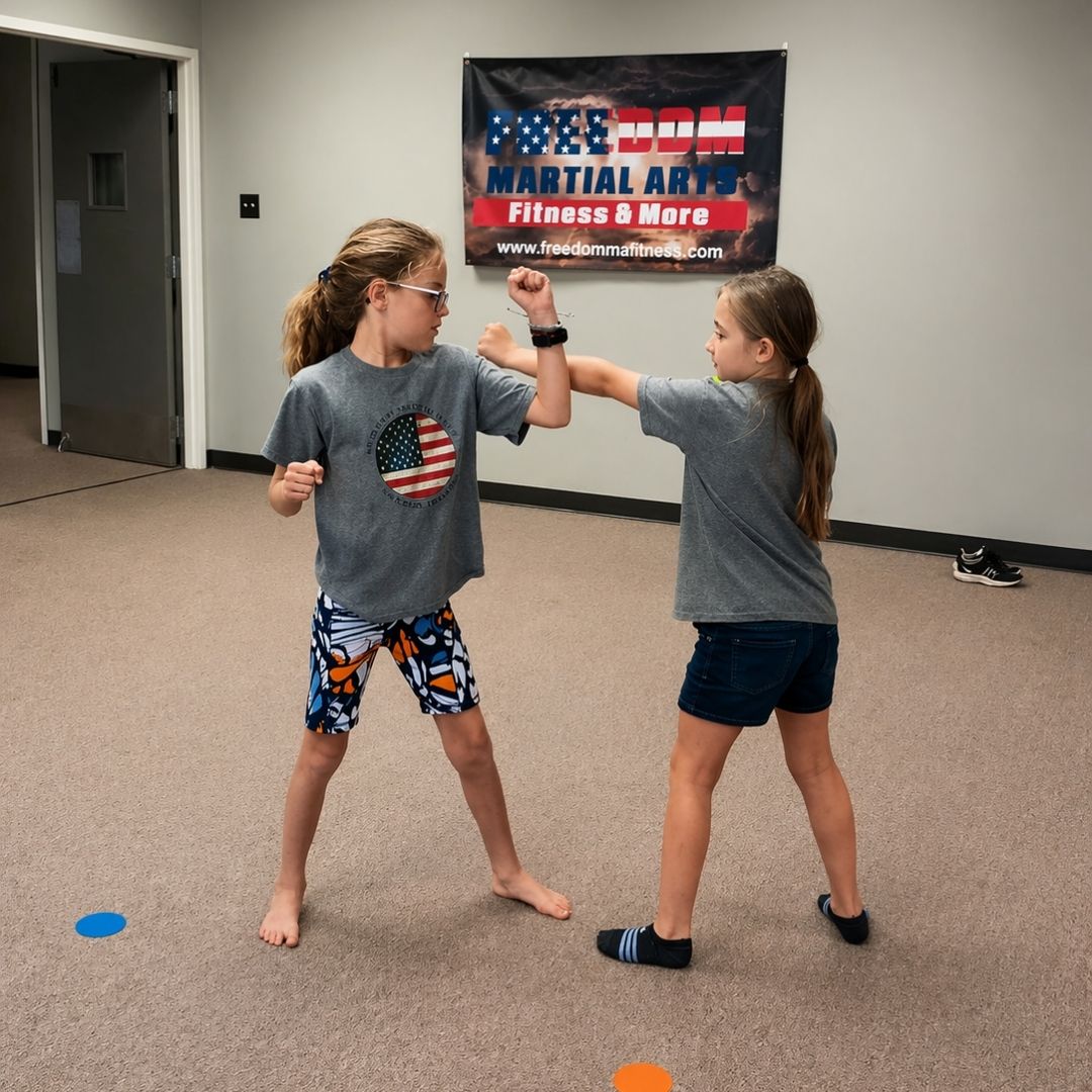 Two people grappling on a mat, one in a black gi, the other in a rash guard, legs entangled.