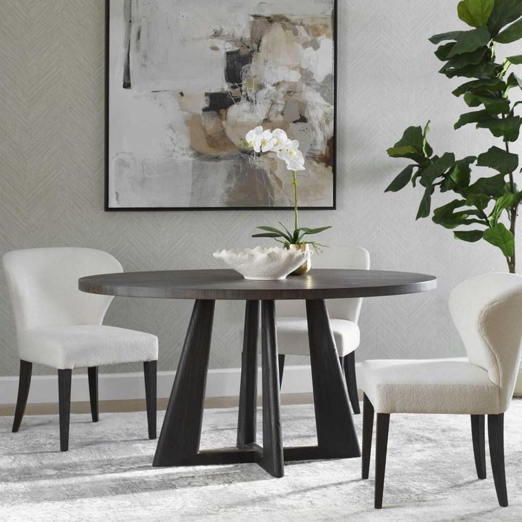 Modern dining room with round table, white chairs, abstract wall art, and potted plant