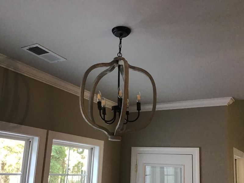 Interior room with a dark metal chandelier hanging from a light gray ceiling above windows and a white door.