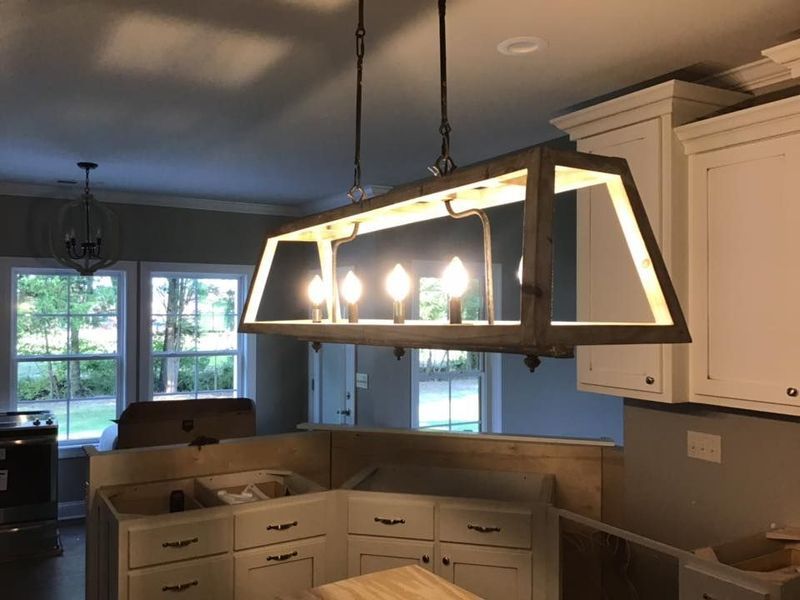 Modern kitchen with large hanging rectangular light fixture above white cabinets and island.