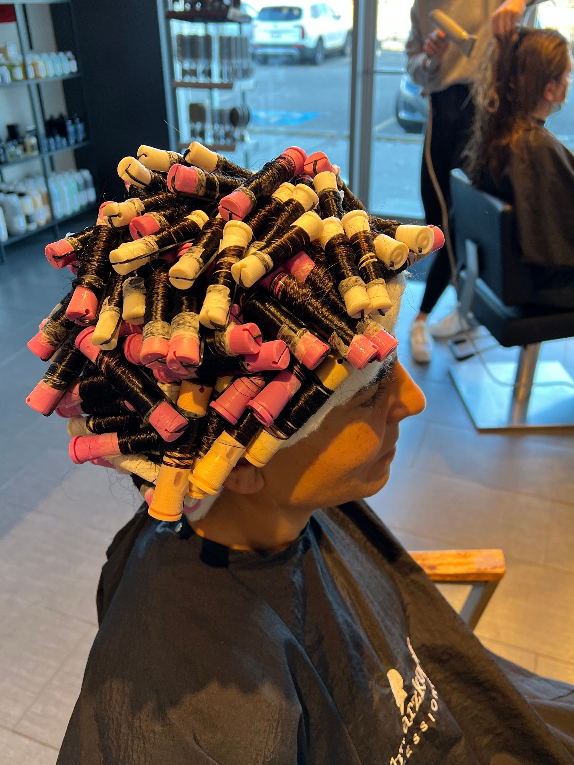 A woman with curlers in her hair is sitting in a chair