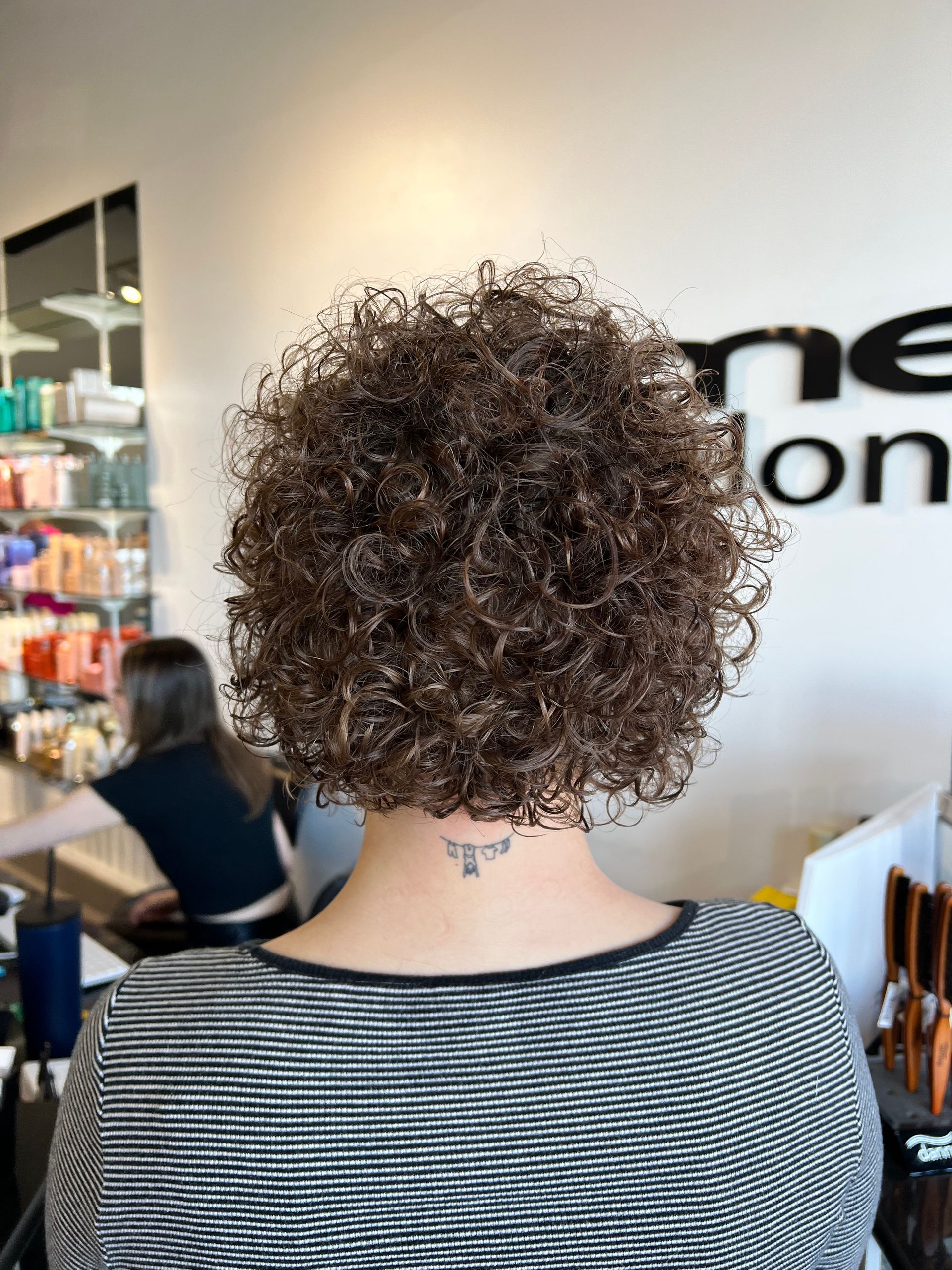 A woman with curly hair is sitting in a salon.