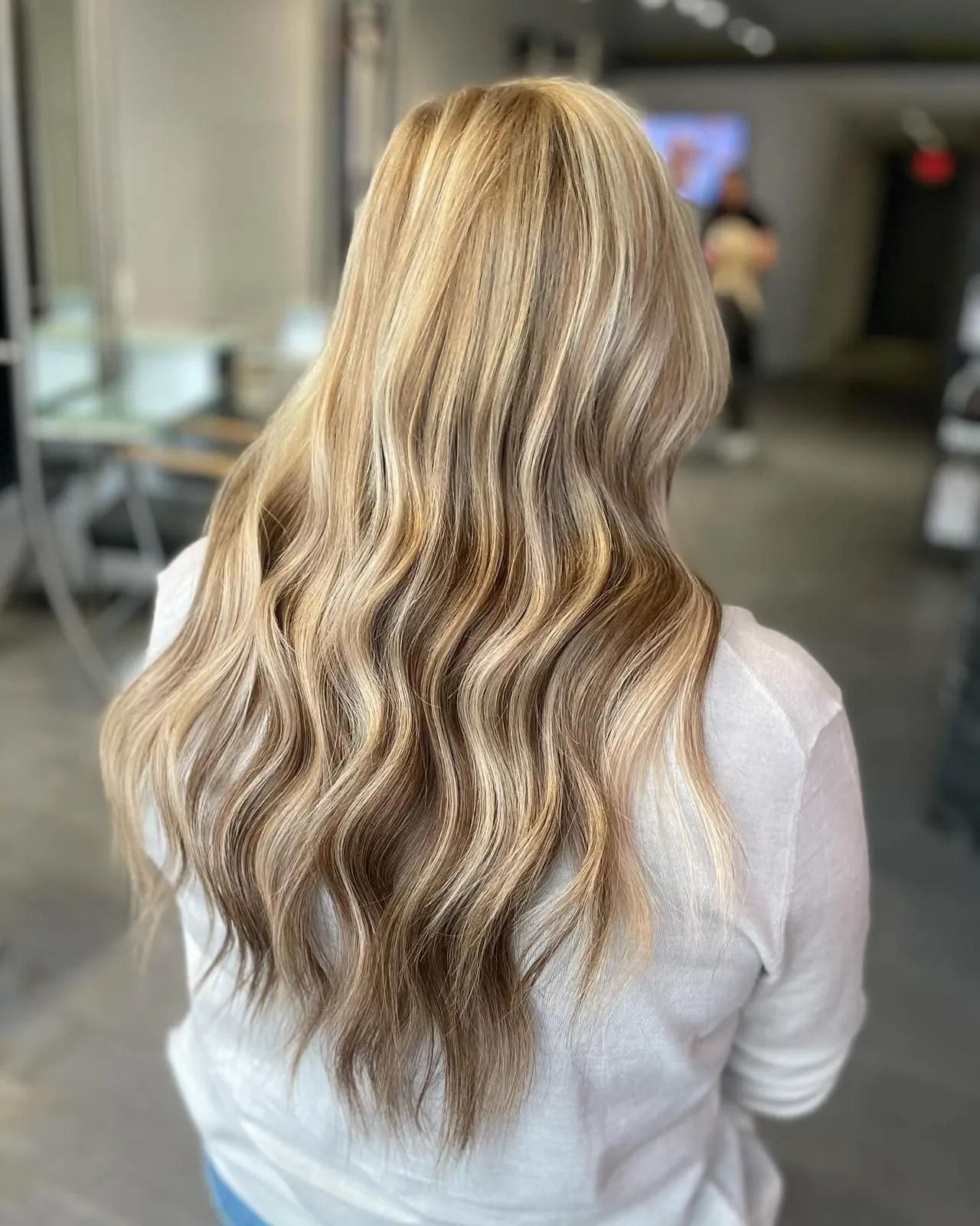 Back view of long wavy blonde hair with highlights in a salon setting
