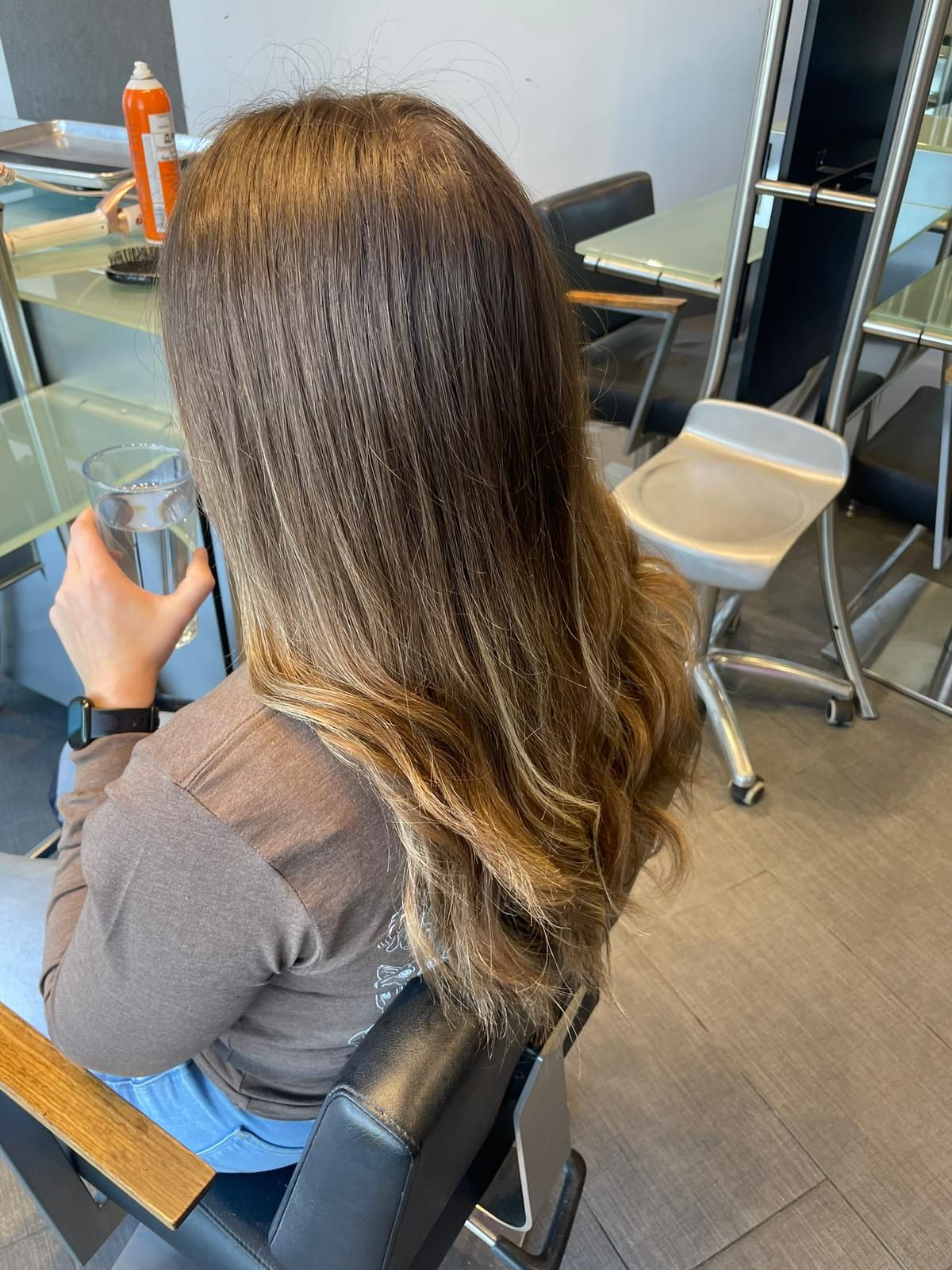 A woman is sitting in a chair holding a glass of water.
