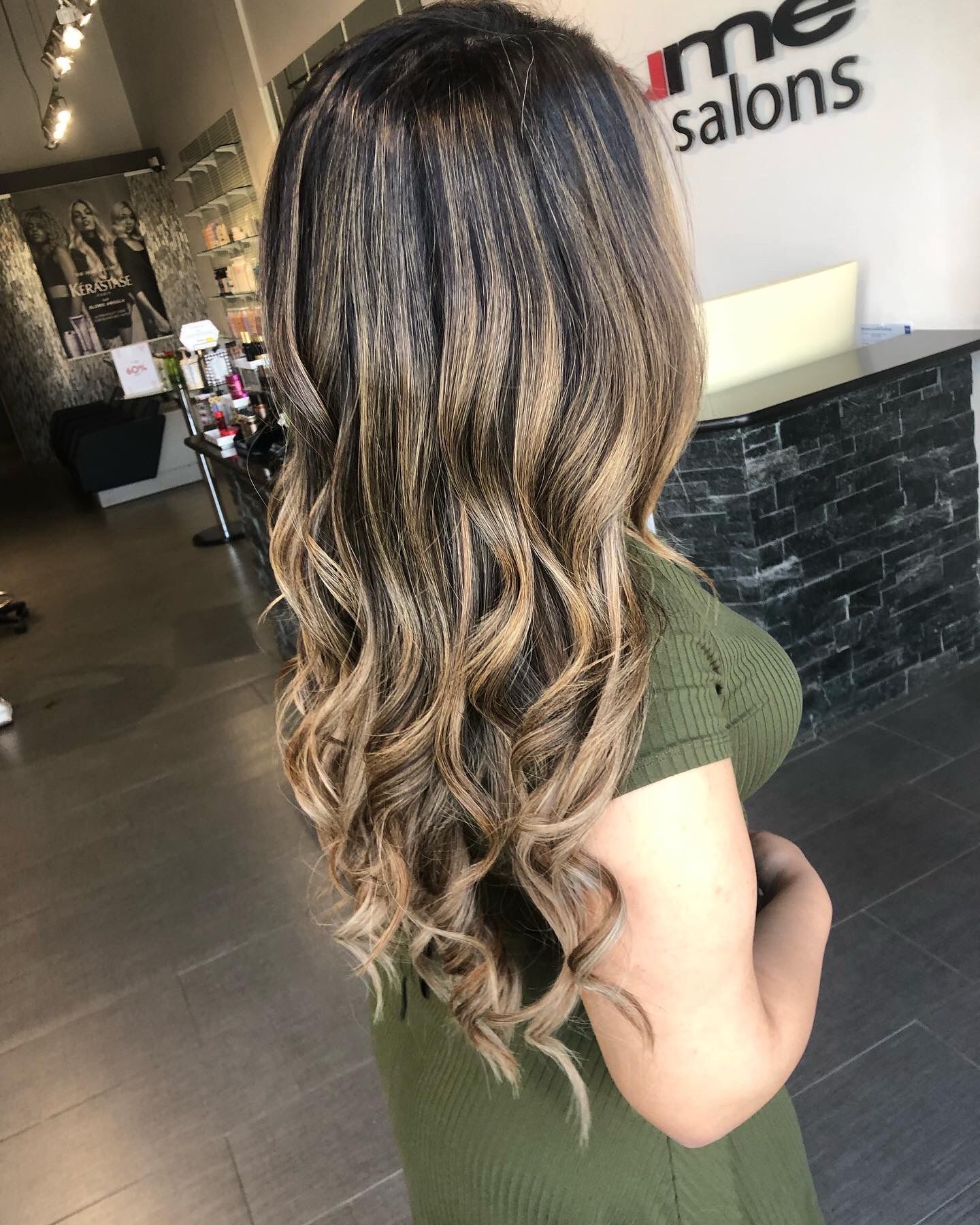 A woman in a green dress is standing in a salon.
