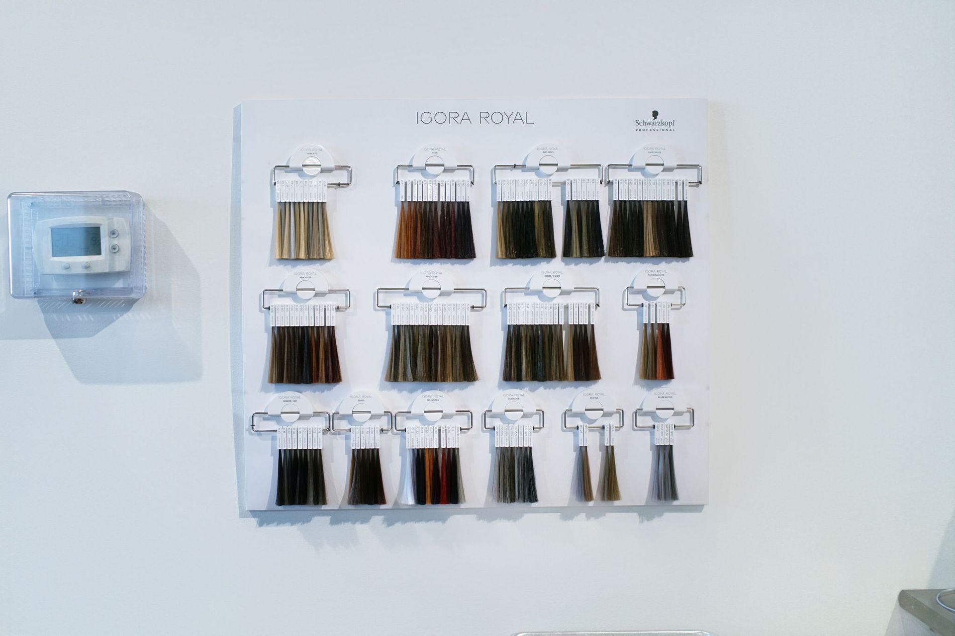 Wall-mounted display of hanging spice or tea bags beside a small control panel on a white wall