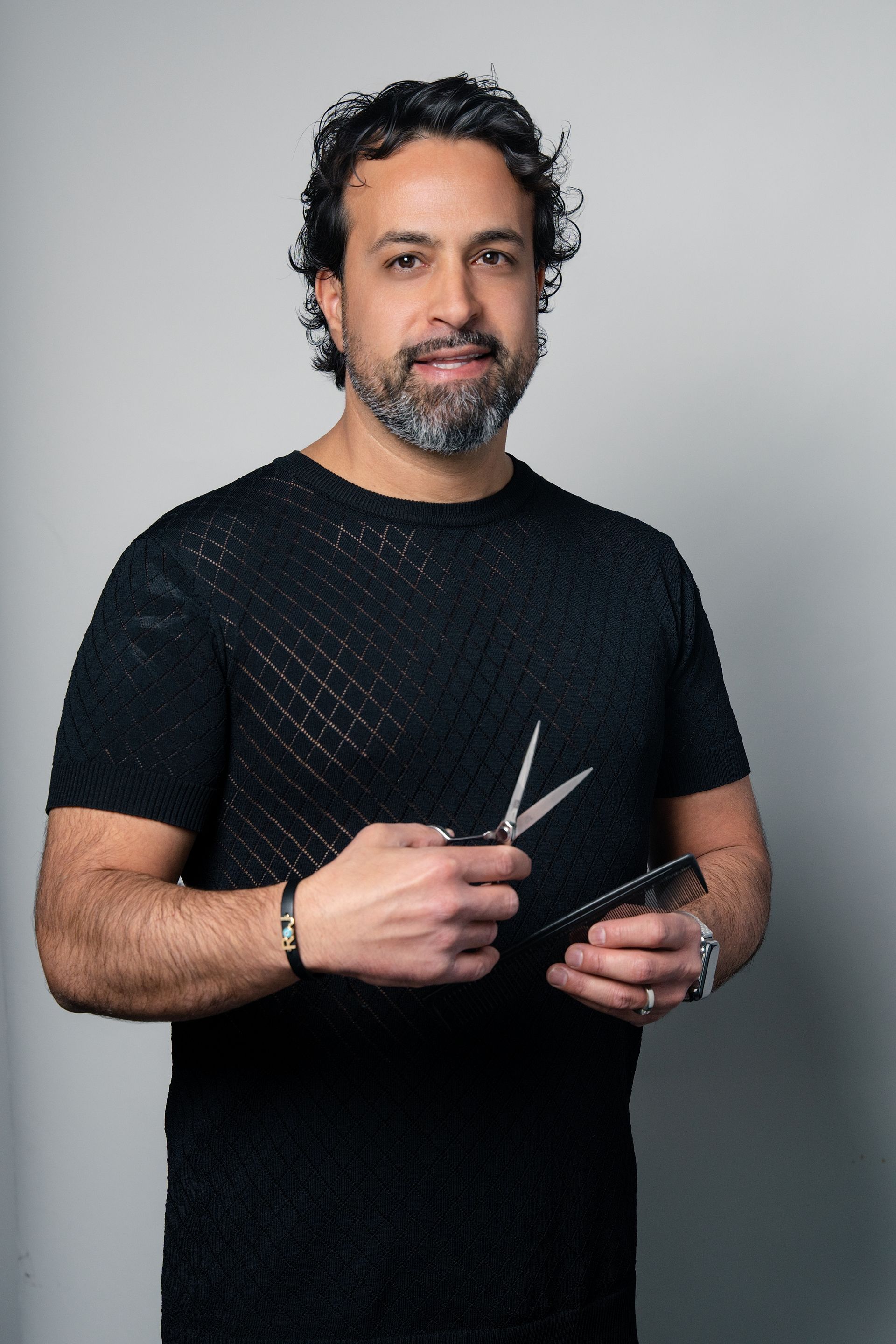 A man in a black shirt is holding a pair of scissors