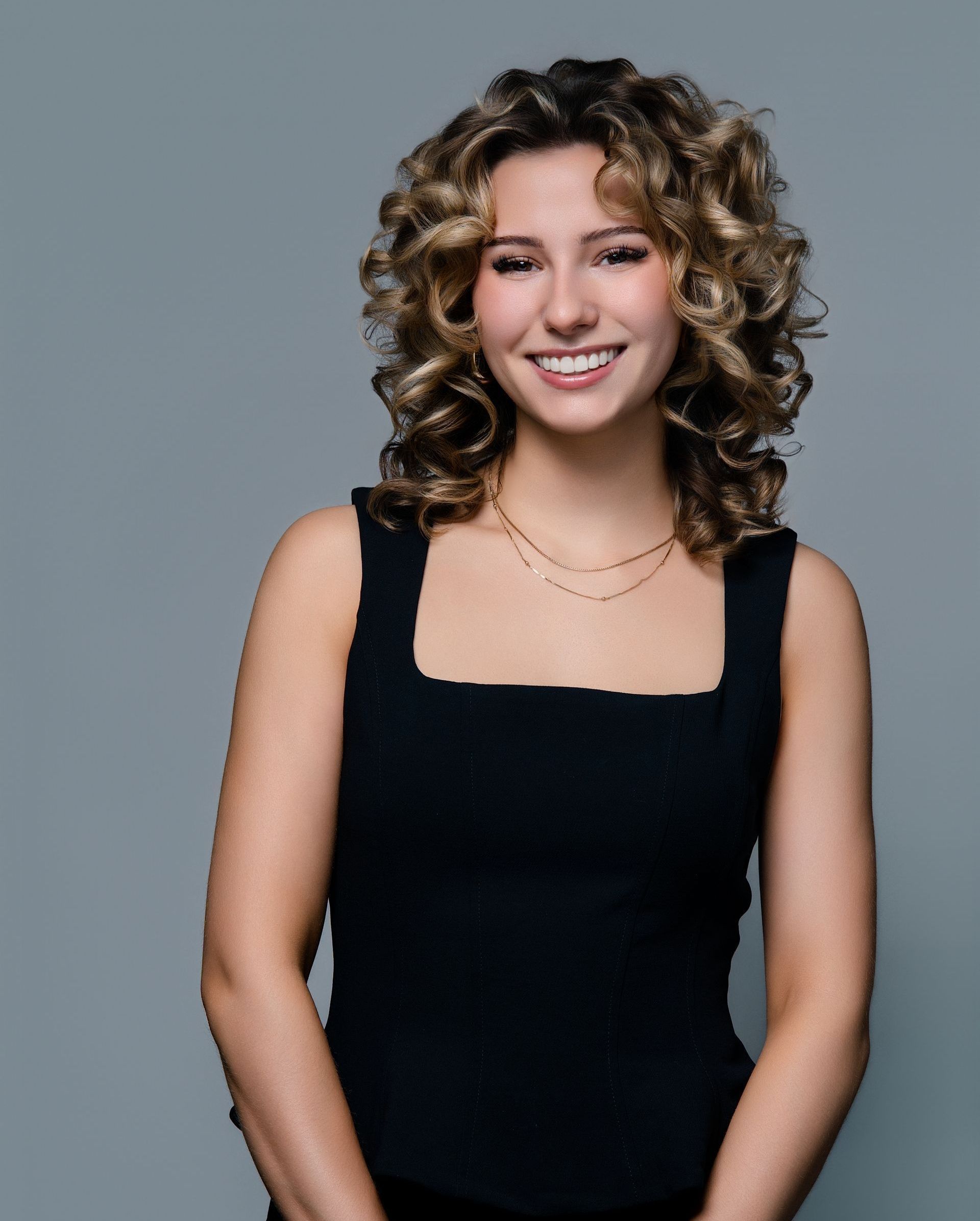A woman with curly hair is wearing a black tank top