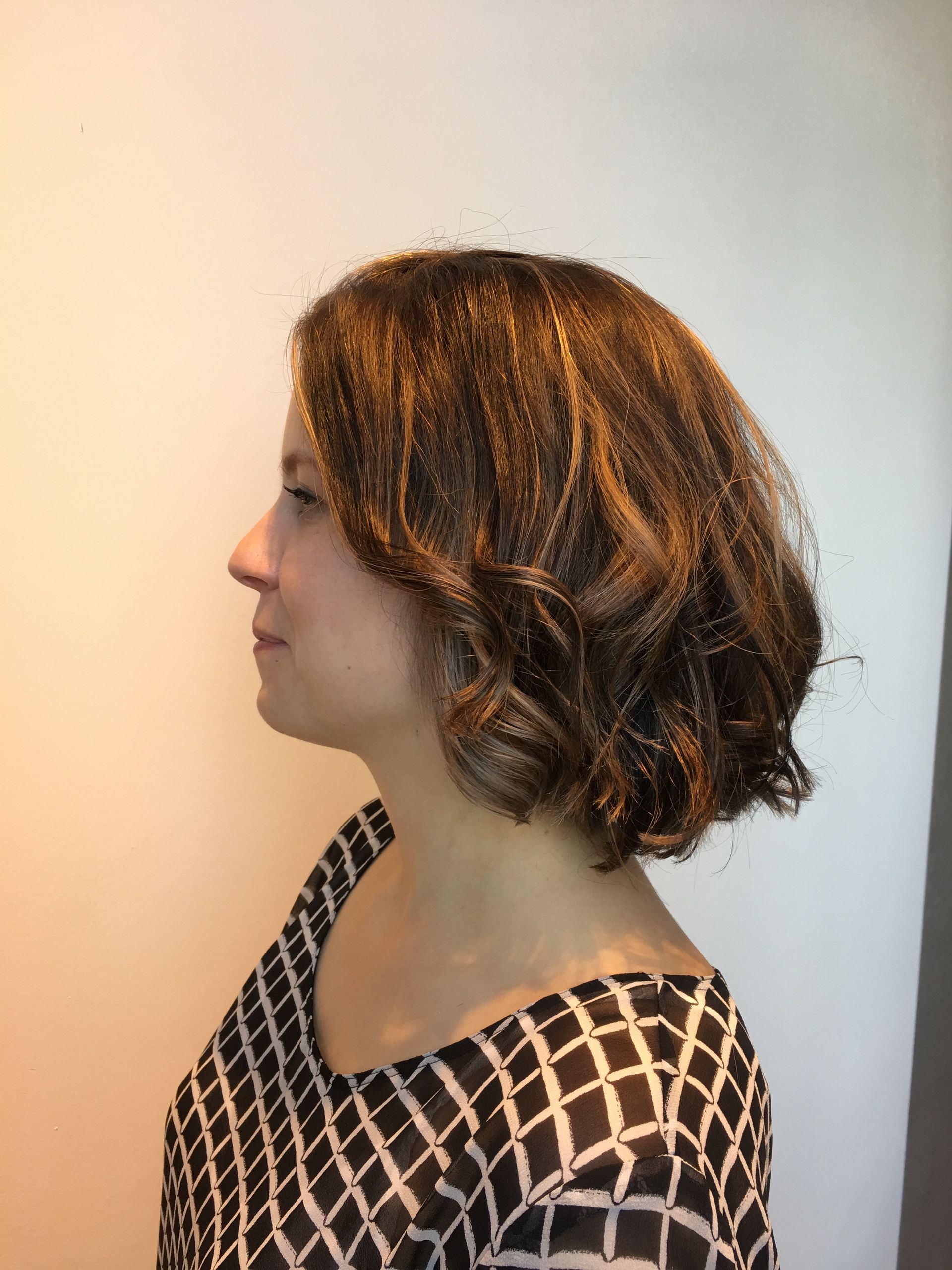A woman with short brown hair is wearing a black and white shirt.