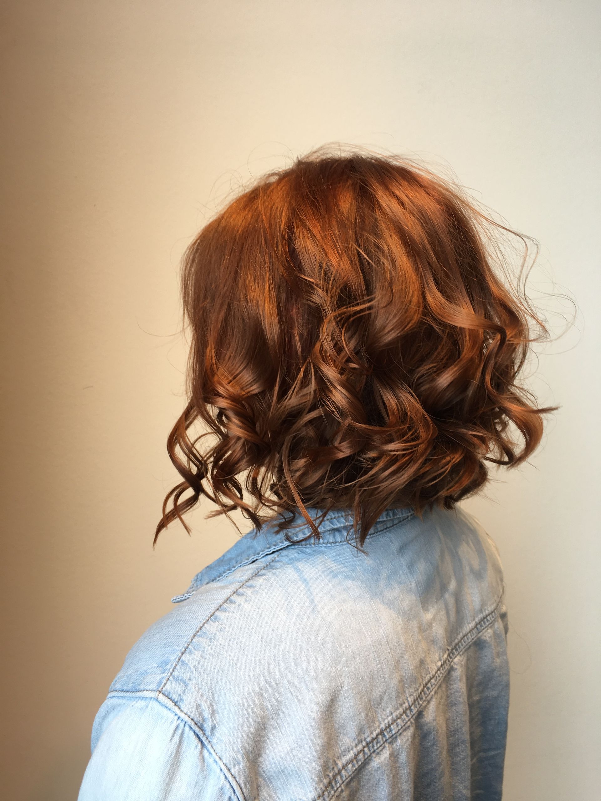 A woman with red curly hair is wearing a denim jacket.