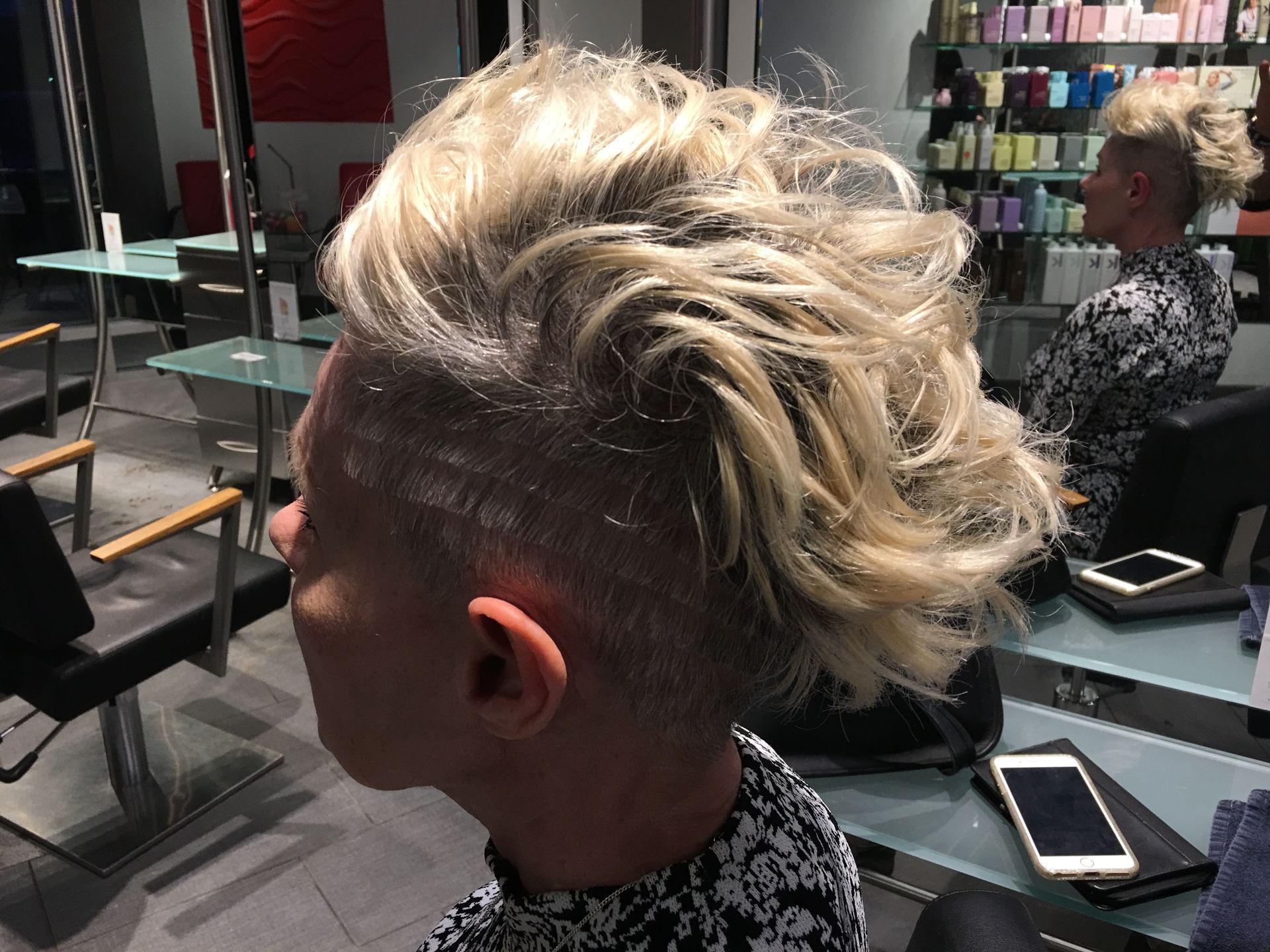 A man with blonde hair is getting his hair cut in a salon.