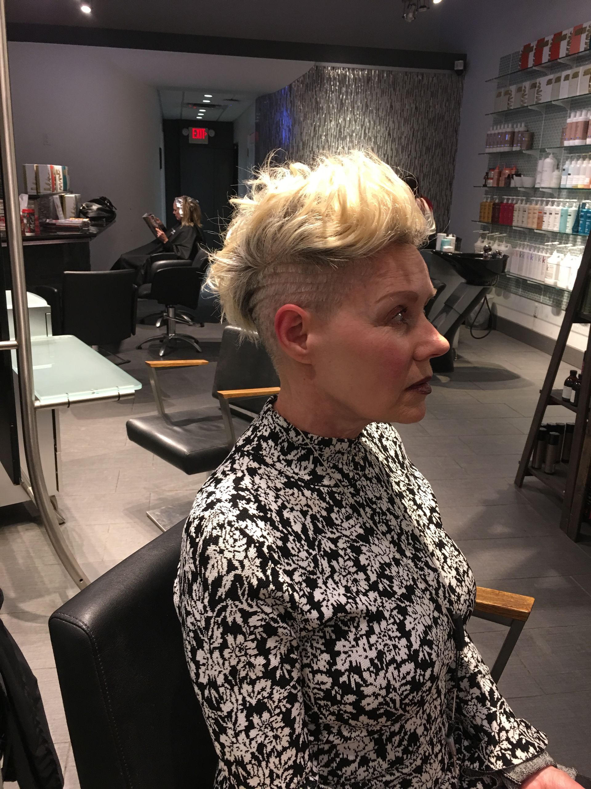 A woman is sitting in a chair in a hair salon.