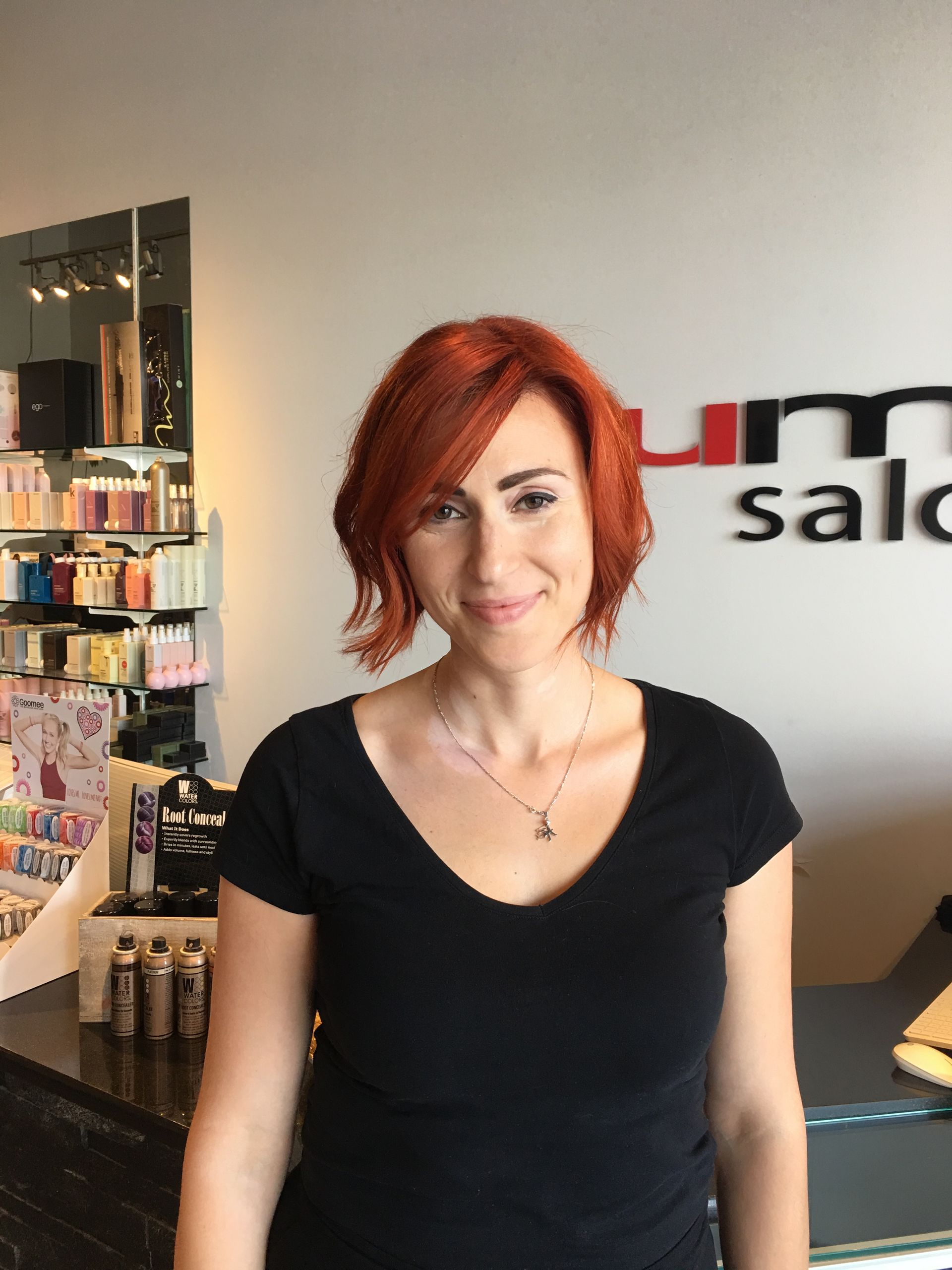 A woman with red hair is standing in front of a sign that says um salon
