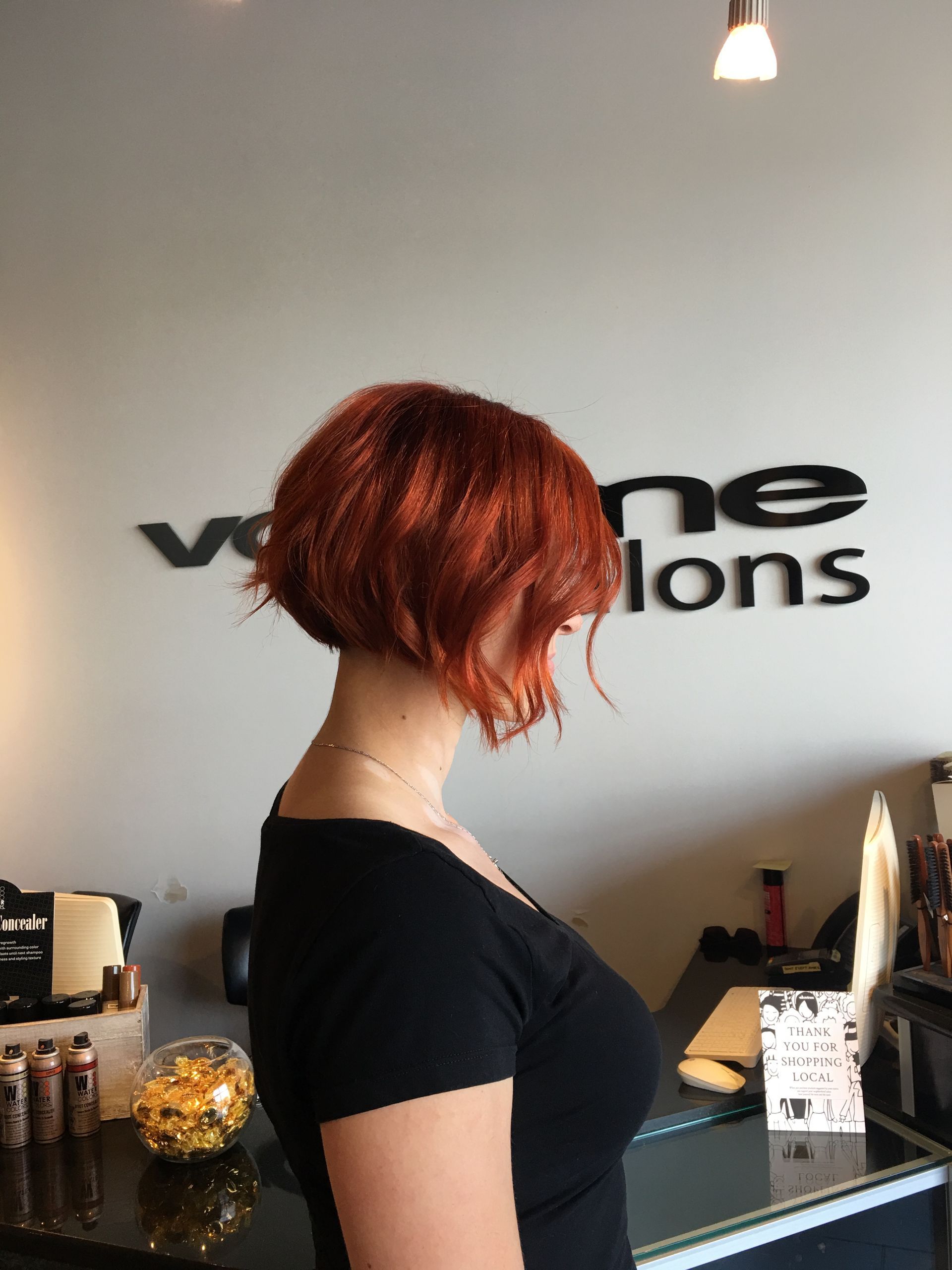 A woman with red hair is standing in front of a sign that says ' vene salons '