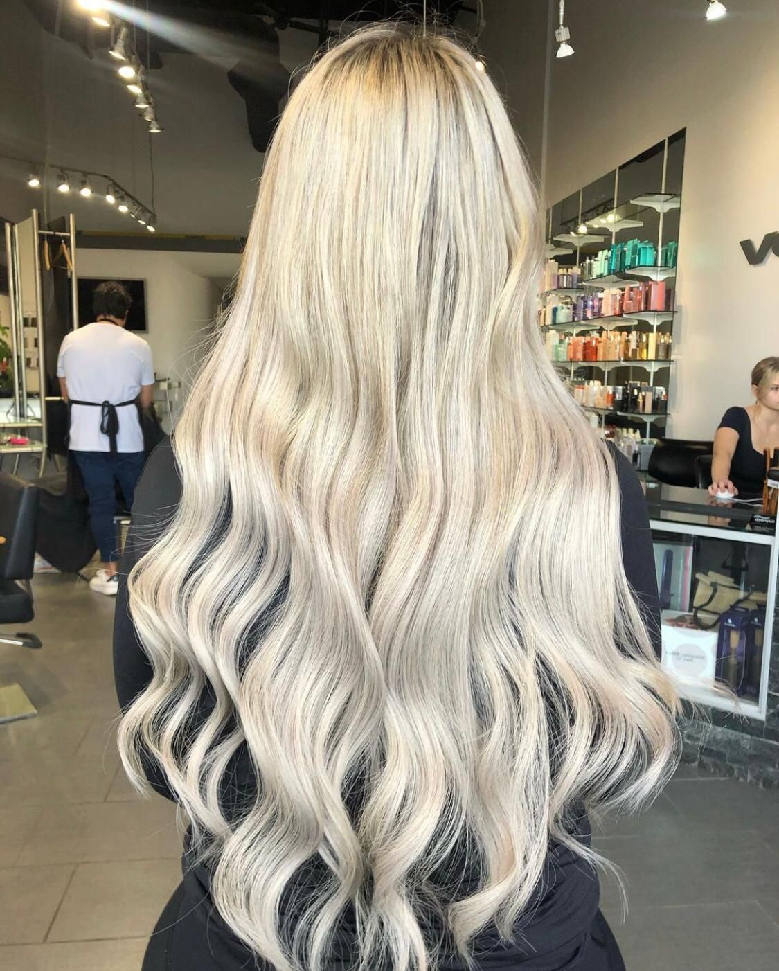 Woman with long, wavy, platinum blonde hair in a salon setting.